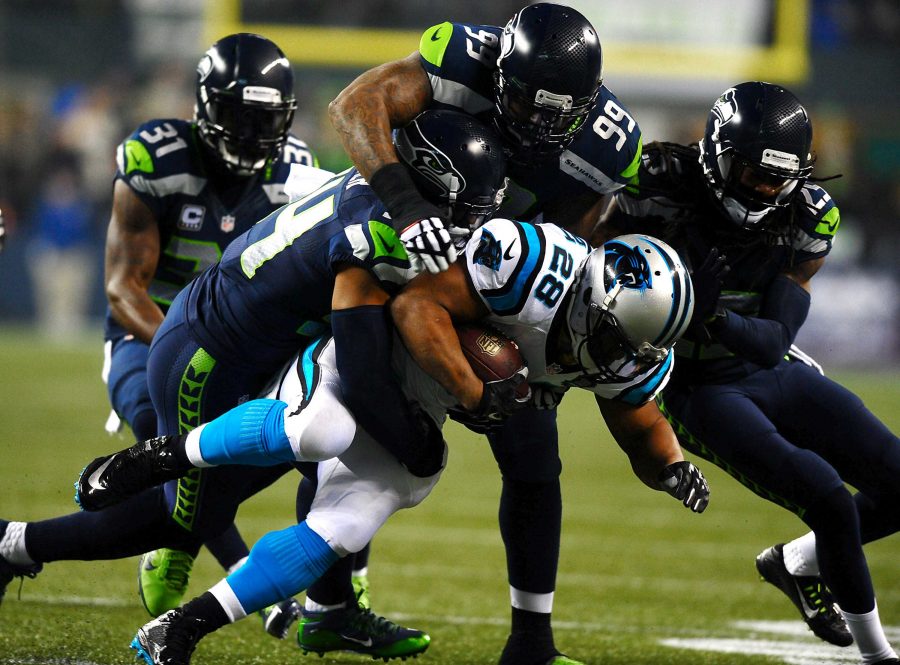 Carolina Panthers running back Jonathan Stewart (28) is tackled by Seattle Seahawks linebacker Bobby Wagner (54), defensive tackle Tony McDaniel (99) and cornerback Richard Sherman (25) on a run during the first quarter in NFC Divisional Playoff action at CenturyLink Field in Seattle on Saturday, Jan. 10, 2015. (Jeff Siner/Charlotte Observer/TNS)