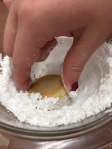 Students finish their snowball cookies by rolling them in powdered sugar. (A. Landman)