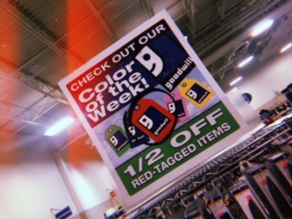 This sign features the Color of the Week, items with specific colored tags designating that they are half off.