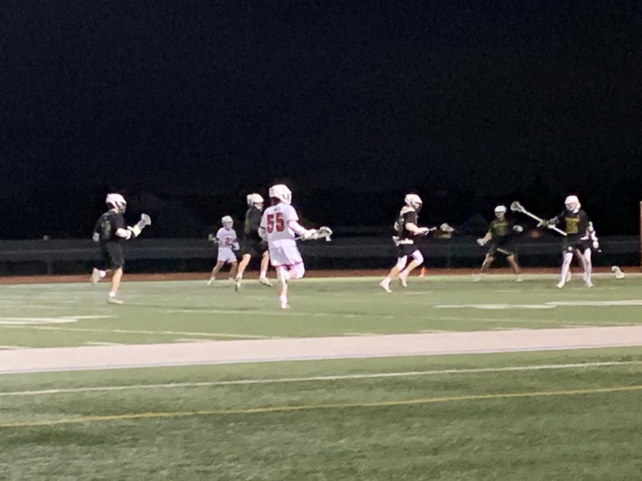 The boys lacrosse team plays against Fremd High School on the Red Raiders football field.