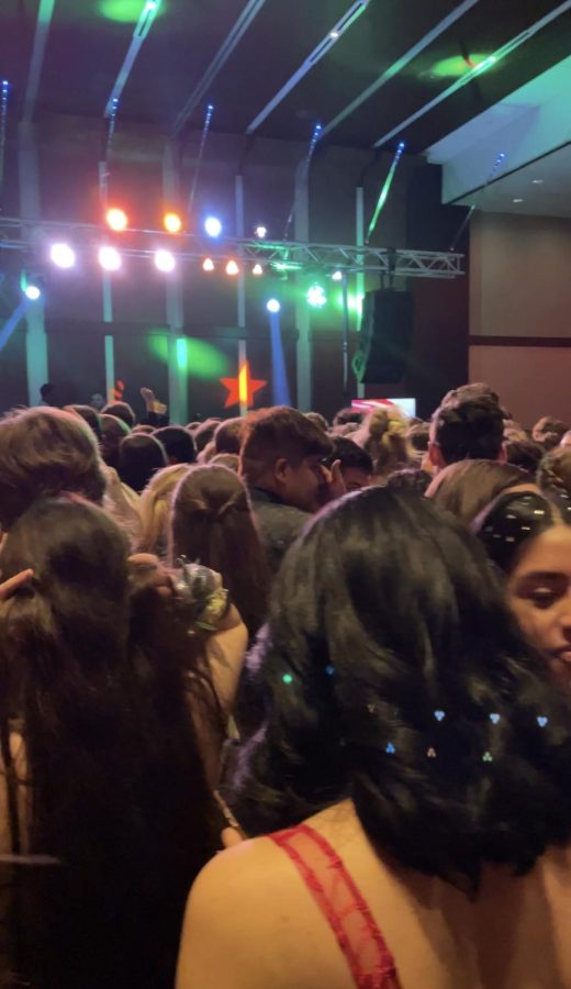 Students at Prom crowd around the DJ on the dance floor.