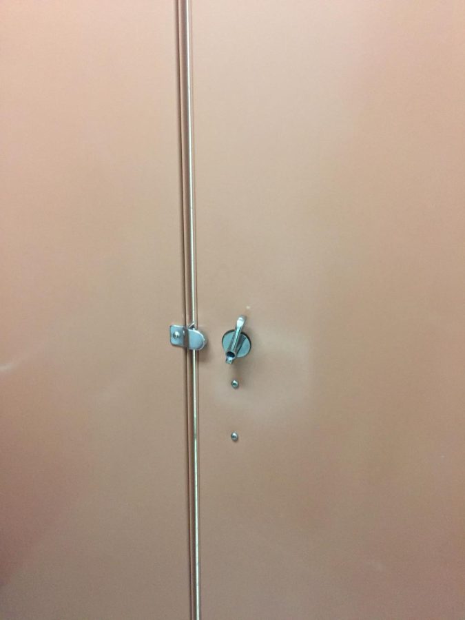 Bathroom stall door being held closed shut with a foot propped up while ignoring the cracks between the door.