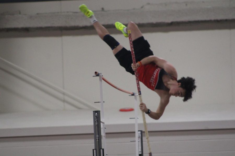 Pole vaulter tries to jump over rod.