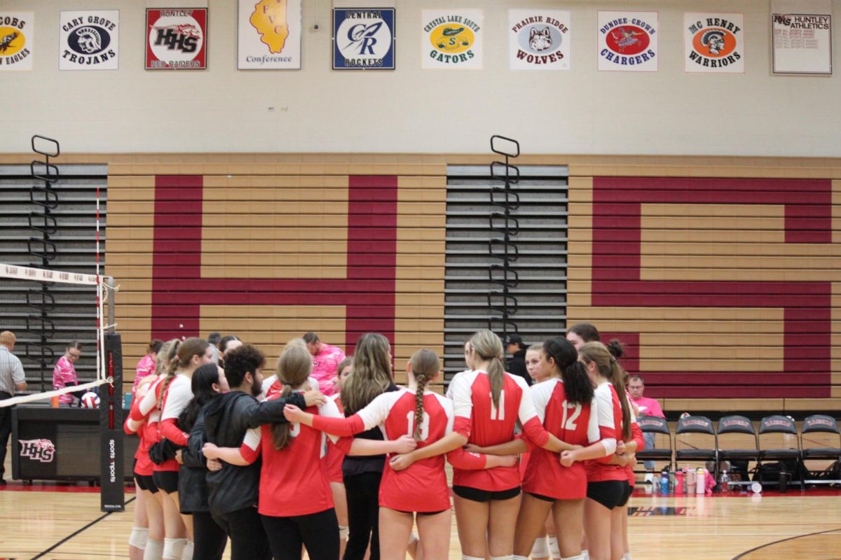 Huntley varsity girls volleyball comes together for a team huddle between sets