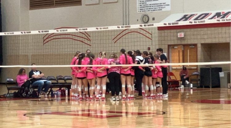 The girls volleyball team huddles and hype themselves up for the big game. 